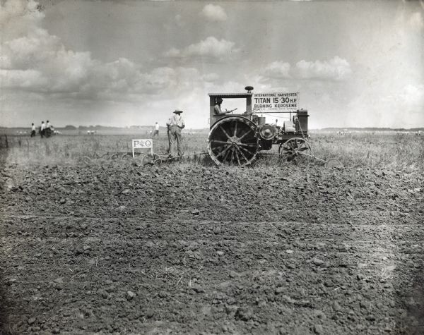 Men plow a field using an International Harvester Titan 15-30 kerosene tractor and a P&O plow. The men were likely participating in a demonstration or show. There is a sign on the the tractor. The original photograph is labeled "Hutchinson," which may refer to Hutchinson, Kansas.