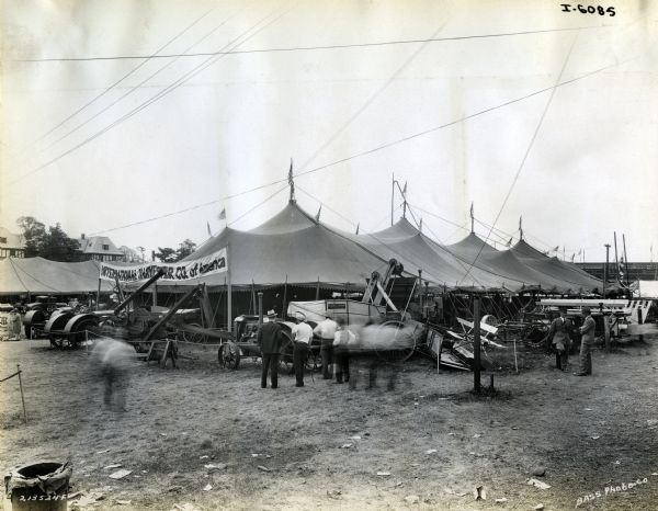 Men gather outside the International Harvester tent at the Indiana State Fair to look at tractors, threshers and other agricultural machines on display.