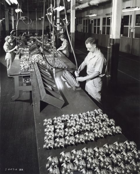 Male and female factory workers use drills or drivers on metal parts at West Pullman Works.