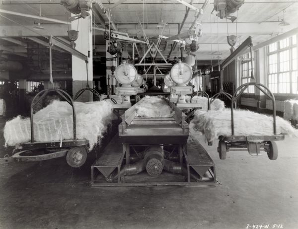 Bundles of twine (fibre) piled on hanging scales are weighed at International Harvester's Hamilton Works factory.