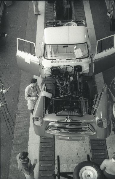 Elevated view of part of a five-man assembly team working on the body of an International A-100 "Golden Jubilee" truck. The fender-grille unit is dropping through an opening in the trim line floor at International Harvester's Springfield Works.