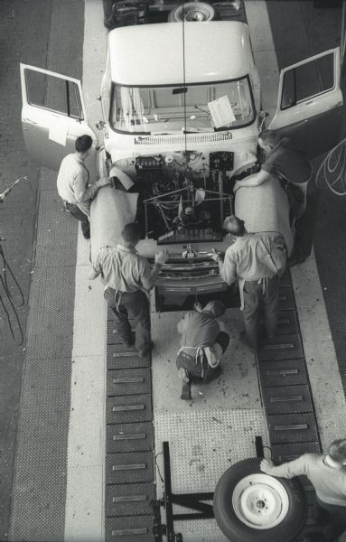 Elevated view of a five-man assembly team working to assemble the cab and chassis of an International A-100 "Golden Jubilee" truck at International Harvester's Springfield Works.