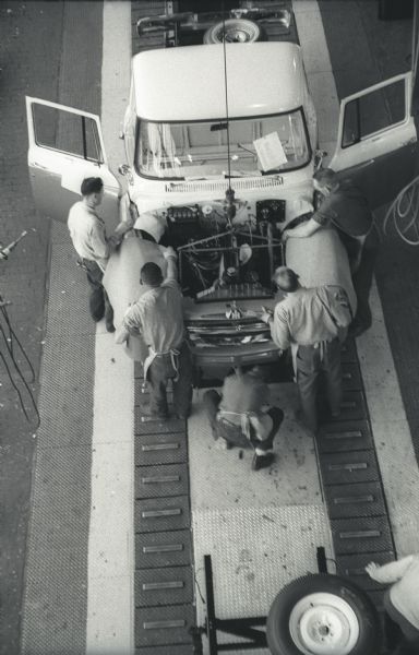 Elevated view of a five-man assembly team working to assemble the cab and chassis of an International A-100 "Golden Jubilee" truck at International Harvester's Springfield Works.