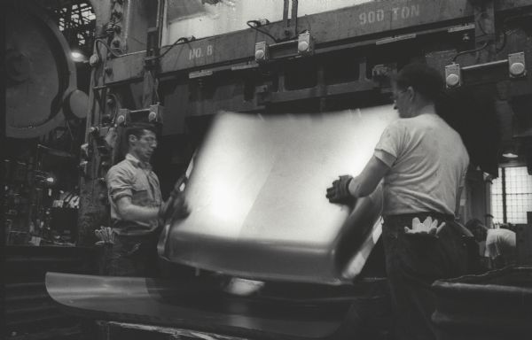 Two factory workers remove an International A-100 "Golden Jubilee"  truck hood from a press at Springfield Works.  The hoods took shape from flat sheets of steel under 700 tons of pressure.