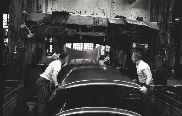Factory workers take an Internatioanl A-100 "Golden Jubilee" truck  hood from a press at International Harvester's Springfield Works.  The hoods took shape from flat sheets of steel under 700 tons of pressure.