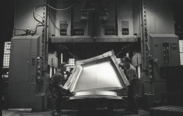 Two factory workers remove an A-100 "Golden Jubilee" truck hood from a press at International Harvester's Springfield Works.  The hoods took shape from flat sheets of steel under 700 tons of pressure.