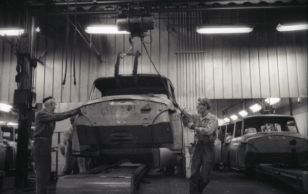 An unidentified factory worker and Lowell Kuhn guide the finished cab of an International A-100 "Golden Jubilee" truck to the paint line at Springfield Works.