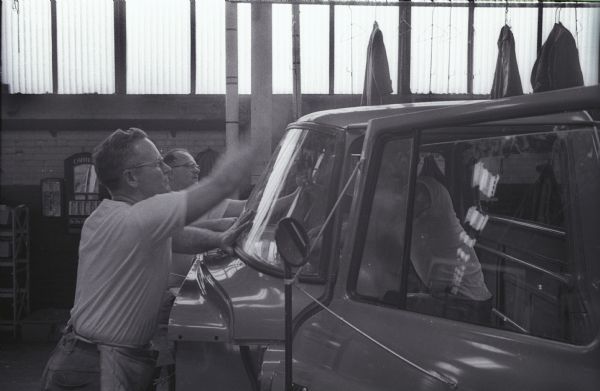 Leo Cross and Albert Overholser place a "sweep-around" windshield onto an International A-100 "Golden Jubilee" truck at International Harvester's Springfield Works factory.