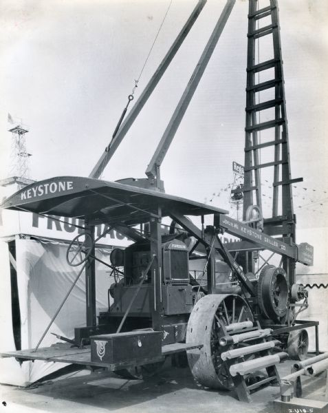 A size 5 1/2 Joplin Special clutch hoist labeled "Keystone Driller Co." is powered by a McCormick-Deering engine and sits on display at the International Petroleum Exposition.