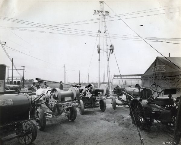 A variety of Samson machines sit on display under a tower with a sign reading: "Samson All Steel Pulling Machine" at the International Petroleum Exposition.