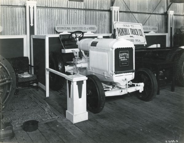 A tractor with a sign reading: "Resistcor Engineering Corp. Distributors" sitting on display inside a building at the International Petroleum Exposition. A sign reading: "International Harvester Co. of America" is in the background.