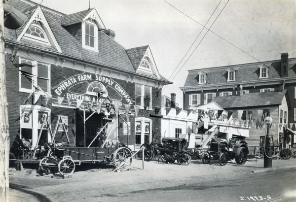 Exterior of an International Harvester dealership with advertising pennants hanging above agricultural machines on display.