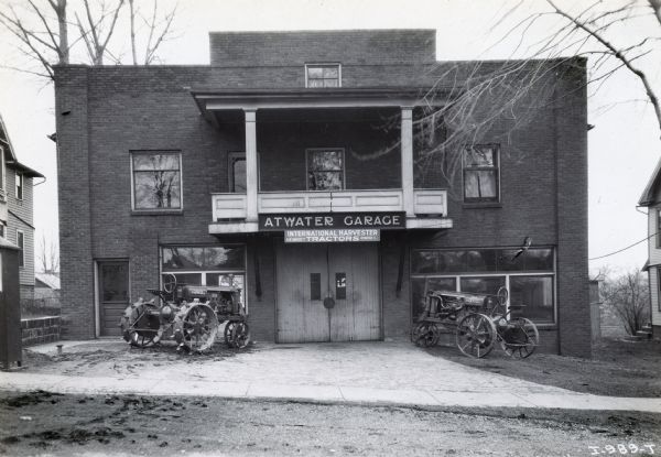 Two tractors are parked on either side of the entrance to the Atwater Garage, an International Harvester dealership.