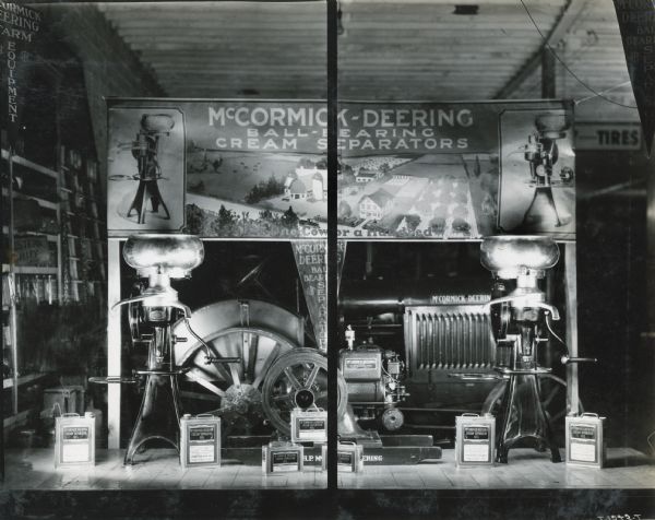 Two ball-bearing cream separators, along with various separator parts and cans of oil, are arranged in the Pilcher Hardware Company display window. Pilcher Hardware Company was an International Harvester dealership in Ida Grove, Iowa. The banner in the background reads: "McCormick-Deering Ball-Bearing Cream Separators; For One Cow or a Hundred."