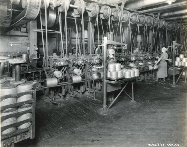 Female factory workers at the McCormick Works twine mill use machines to wind twine onto spools.