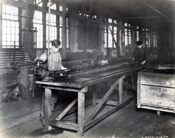 Factory workers handle chain in the chain department, possibly at  McCormick Works.