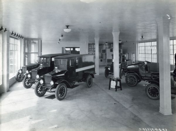 International trucks a showroom lined with windows, possibly at the International Harvester Company service station No. 3. A display sign in the center of the room reads: "This is the crankshaft and these are the ball bearings; Guaranteed for Life."