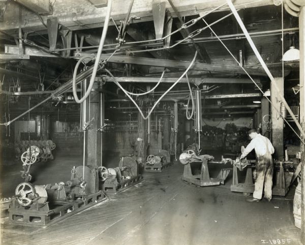 Factory worker assembles machines at International Harvester's McCormick Works. The machines are loaded on carts that roll along a track embedded in the floor.