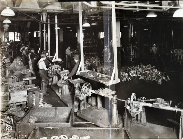 Factory workers use machinery surrounded by bins of metal parts at McCormick Works.
