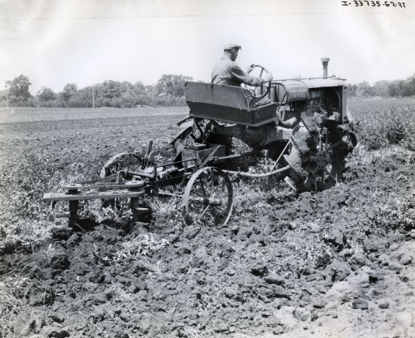 A man is driving a Farmall tractor and attachment through a field. The handwritten text below the photograph identifies either the tractor or the attachment as being "experimental."