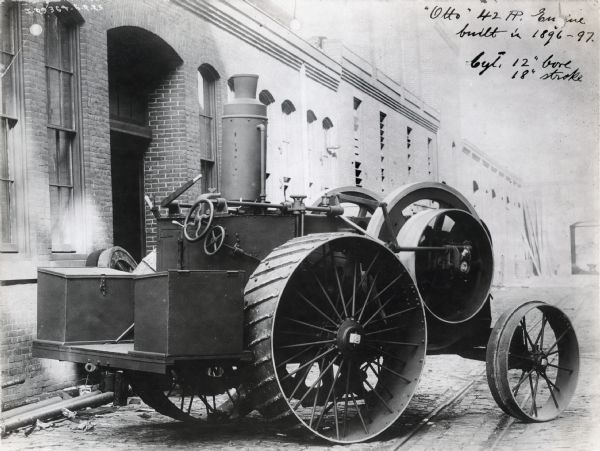 42 horsepower Otto traction engine built in 1896-1897, sits on the street in front of a brick building. The original caption reads, "Cyl. 12" bore; 18" stroke."  The "Otto" cycle engine was first patented by Eugenio Barsanti and Felice Matteucci in 1854 followed by the first prototype in 1860. The "Otto" engine is characterized by four strokes.