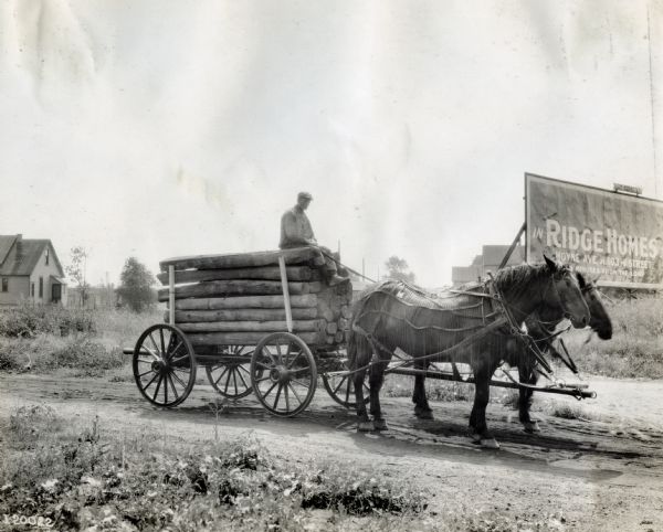 A man drives a wagon pulled by two horses down a dirt road near a large billboard. The wagon is filled with wooden beams. The sign on the side of the road reads: "...in Ridge Homes; Hoyne Ave. at 103rd Street; ...Minutes from the Loop."