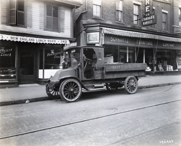 International model "F" or "31" truck operated by Schwartz Furniture Co. of New London, Connecticut. The truck is photographed on the street outside of the Schwartz Furniture Company Store. The New England Lunch Room is also pictured in the background.