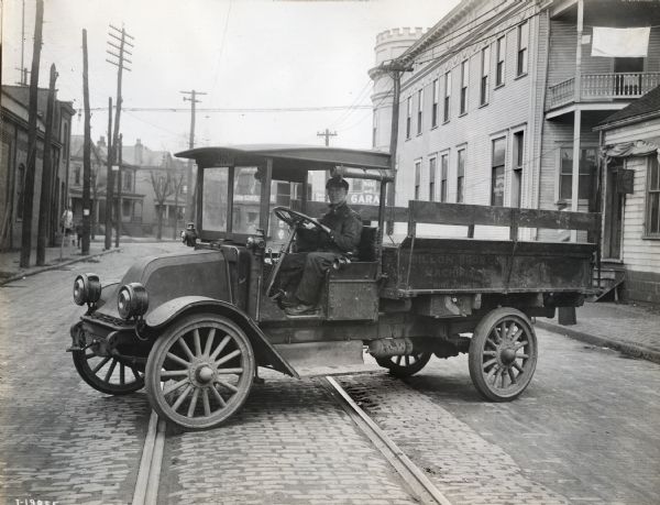 International model "F" or "31" truck operated by Dillon Bros. Co., "machinists" of Wheeling. A man sits in the driver's seat of the truck which is parked on a city street over streetcar(?) tracks.