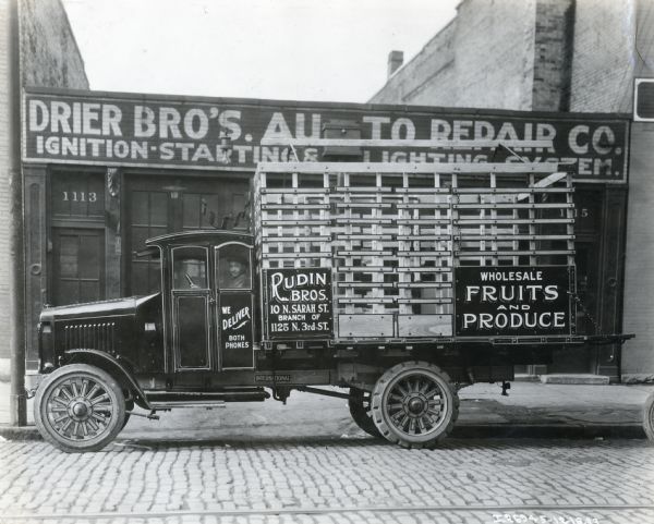International Model "63" truck operated by Rudin Bros. "Wholesale Fruits and Produce." The Rudin Bros. addresses are written on the side of the truck and are: "10 N. Sarah St. Branch of 1125 N. 3rd St." The truck and it's driver were photographed outside of the Drier Bro's. Auto Repair Co.