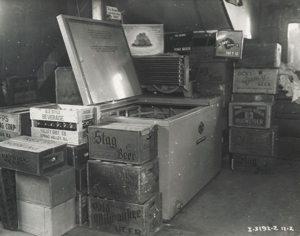 Wooden crates are piled around a McCormick-Deering 6-can milk cooler used for cooling beer at Mr. Jay Winter's tavern.