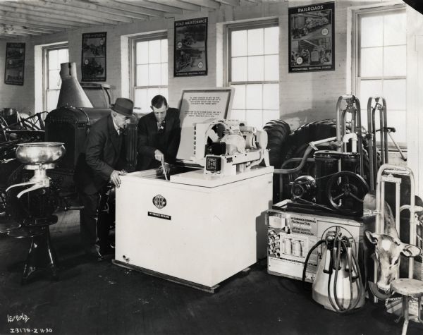 Two McCormick-Deering dealers look into a 4-can milk cooler on display at the Industrial Tractor and Equipment Company.