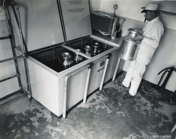 Elevated view of H.C. Wuesthoof putting a milk canister into what a 10 can McCormick-Deering Milk Cooler.