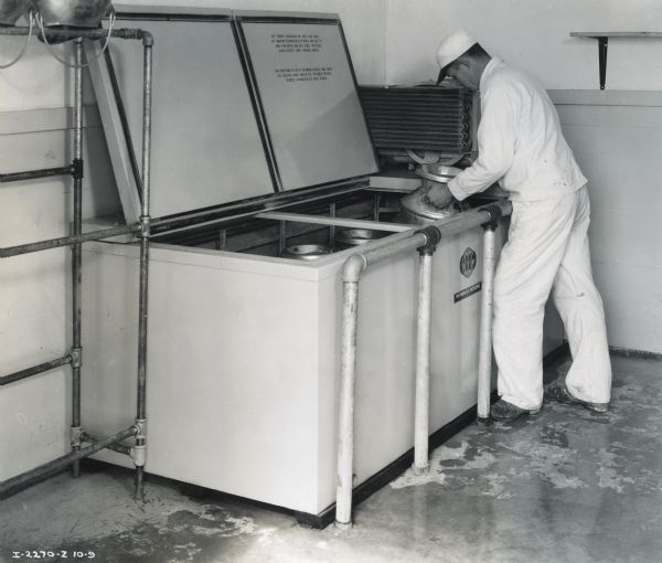 H.C. Wuesthoof places a milk canister into a 10 can McCormick-Deering Milk Cooler.