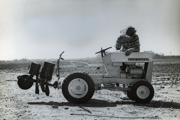 Butch Quirk with a Cub Cadet tractor. Original magazine caption states: "Scientific farmer Quirk uses tractor hood as desk top as he records variety of corn planted and date. When his corn is grown, Butch must face up to the one old-fashioned chore on his highly mechanized three acres--picking corn by hand. Also ahead: problems of marketing."
