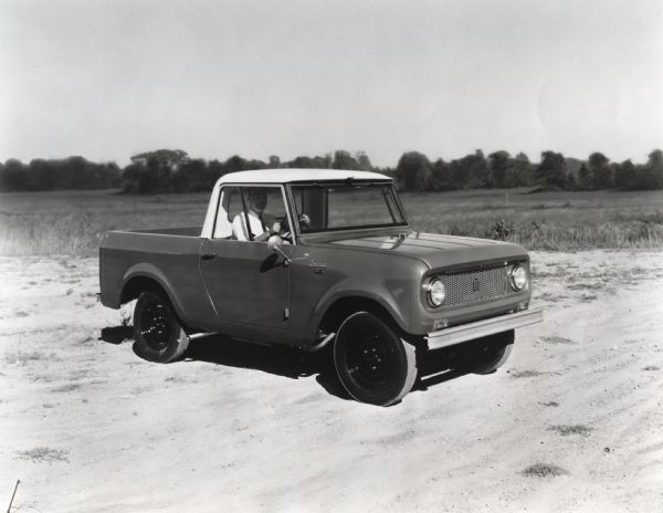 A man is shown behind the wheel of a right-hand drive International Harvester Scout.