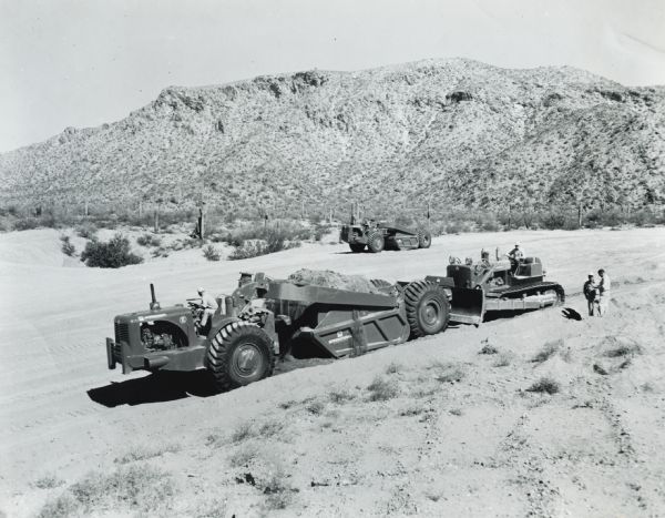 Men operate three International Harvester earthmovers at the company's Phoenix Proving Grounds.