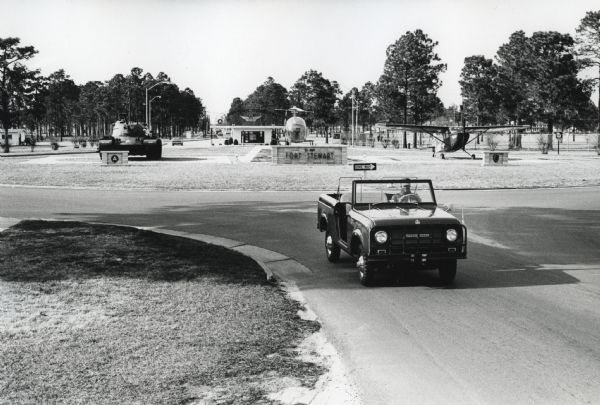 A man drives an International Harvester Scout past military vehicles on display near the entrance to Fort Stewart.