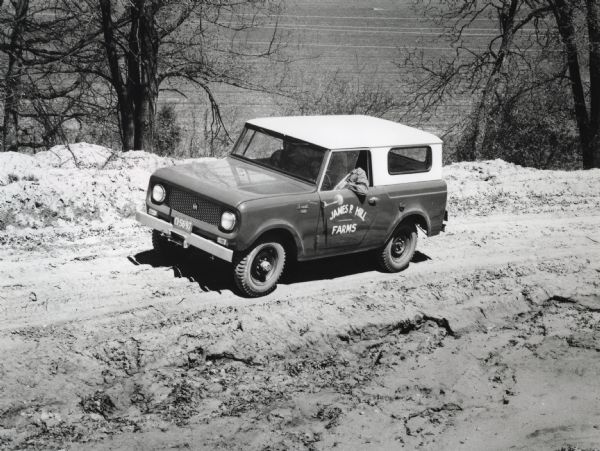An International Harvester Scout used by James P. Hill Farms is driven down a dirt road.