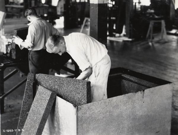 Two factory workers at the West Pullman Works install cork insulation in a McCormick-Deering Milk Cooler.