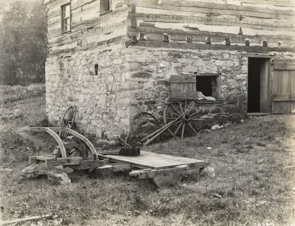 A production still for the Fox Hearst film "Romance of the Reaper". The film was produced by International Harvester at Walnut Grove to celebrate the Reaper Centennial. Caption on back of photograph reads: "Close-up of reaper in further stage of development being built up outside the forge shop."