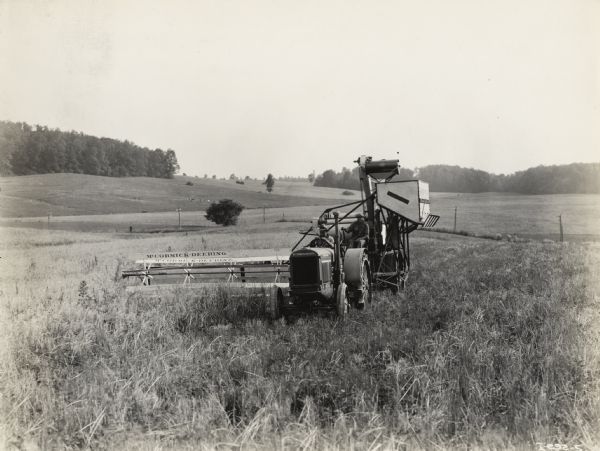 A production still from the Fox Hearst film "Romance of the Reaper." The film was produced by International Harvester at Walnut Grove to celebrate the Reaper Centennial. Two men are operating a McCormick-Deering harvester-thresher (combine), which is pulled by a tractor.