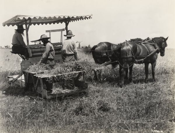 A production still for the Fox Hearst film "Romance of the Reaper". The film was produced by International Harvester at Walnut Grove to celebrate the Reaper Centennial. Three men operate a Marsh Harvester pulled by a two-horse team.