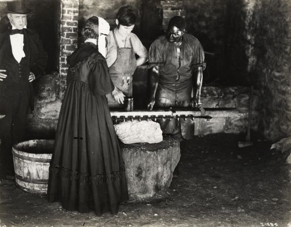 A production still for the Fox Hearst film "Romance of the Reaper". The film was produced by International Harvester at Walnut Grove to celebrate the Reaper Centennial. From left to right: Unidentified actor, Miss Geraldine Woods, the professional actress who played the role of Mary Ann Hall McCormick, Del McDermid, the professional actor who played the role of Cyrus Hall McCormick, and Harry Wilson, who played the role of Jo Anderson.