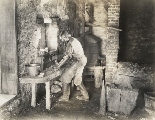 A production still for the Fox Hearst film "Romance of the Reaper". The film was produced by International Harvester at Walnut Grove to celebrate the Reaper Centennial. The actor Harry Wilson (playing the role of Jo Anderson) works in the forge shop.
