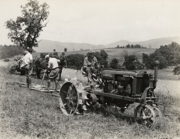 A production still for the Fox Hearst film "Romance of the Reaper". The film was produced by International Harvester at Walnut Grove to celebrate the Reaper Centennial. Men are operating a camera on a platform pulled by a Farmall Regular tractor. The men are filming a replica reaper in a reaping scene.