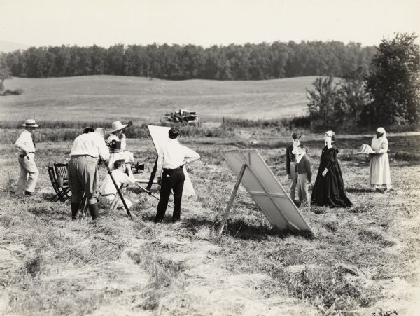 A production still for the Fox Hearst film "Romance of the Reaper". The film was produced by International Harvester at Walnut Grove to celebrate the Reaper Centennial. A crew films a scene with Miss Geraldine Woods (in the role of Mary Ann Hall McCormick), two unidentified actors who played the roles of the younger McCormick brothers, and Clara Wilson (in the role of a house servant).