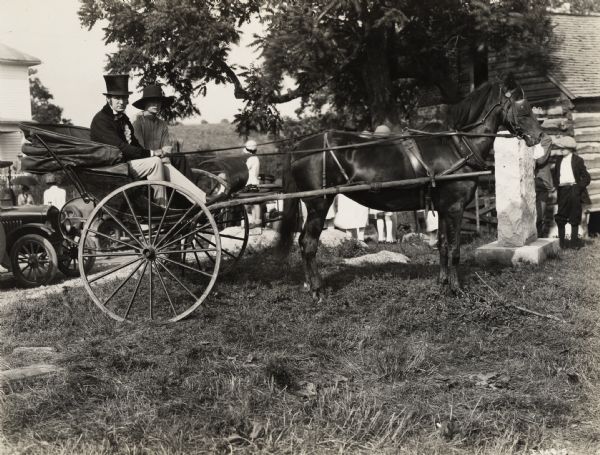A production still for the Fox Hearst film "Romance of the Reaper." The film was produced by International Harvester at Walnut Grove to celebrate the Reaper Centennial. Two men sit in a horse-drawn carriage. The man wearing a top hat is Del McDermid in the role of Cyrus Hall McCormick.