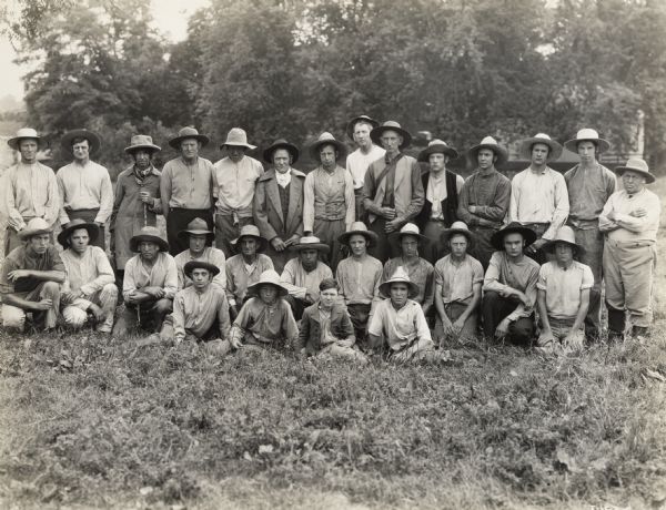 A production still for the Fox Hearst film "Romance of the Reaper." The film was produced by International Harvester at Walnut Grove to celebrate the Reaper Centennial. A large group of men, probably local residents, are posing in a field on or near location for the film "Romance of the Reaper." Some or all of the men may have appeared in the film as extras.