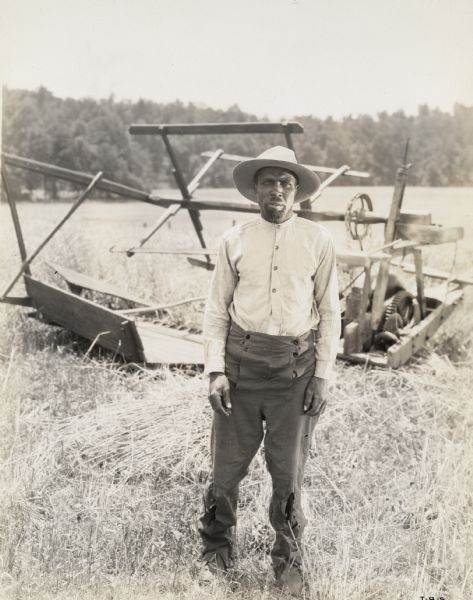 A production still for the Fox Hearst film "Romance of the Reaper." The film was produced by International Harvester at Walnut Grove to celebrate the Reaper Centennial. A man dressed as a farmer stands in front of a replica of McCormick's first reaper. The man may have been a local resident recruited for the film.