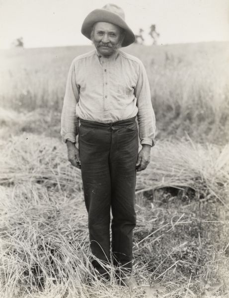 A production still for the Fox Hearst film "Romance of the Reaper". The film was produced by International Harvester at Walnut Grove to celebrate the Reaper Centennial. A man stands in a field, dressed as a farmer. The man may have been a local resident recruited for the film.